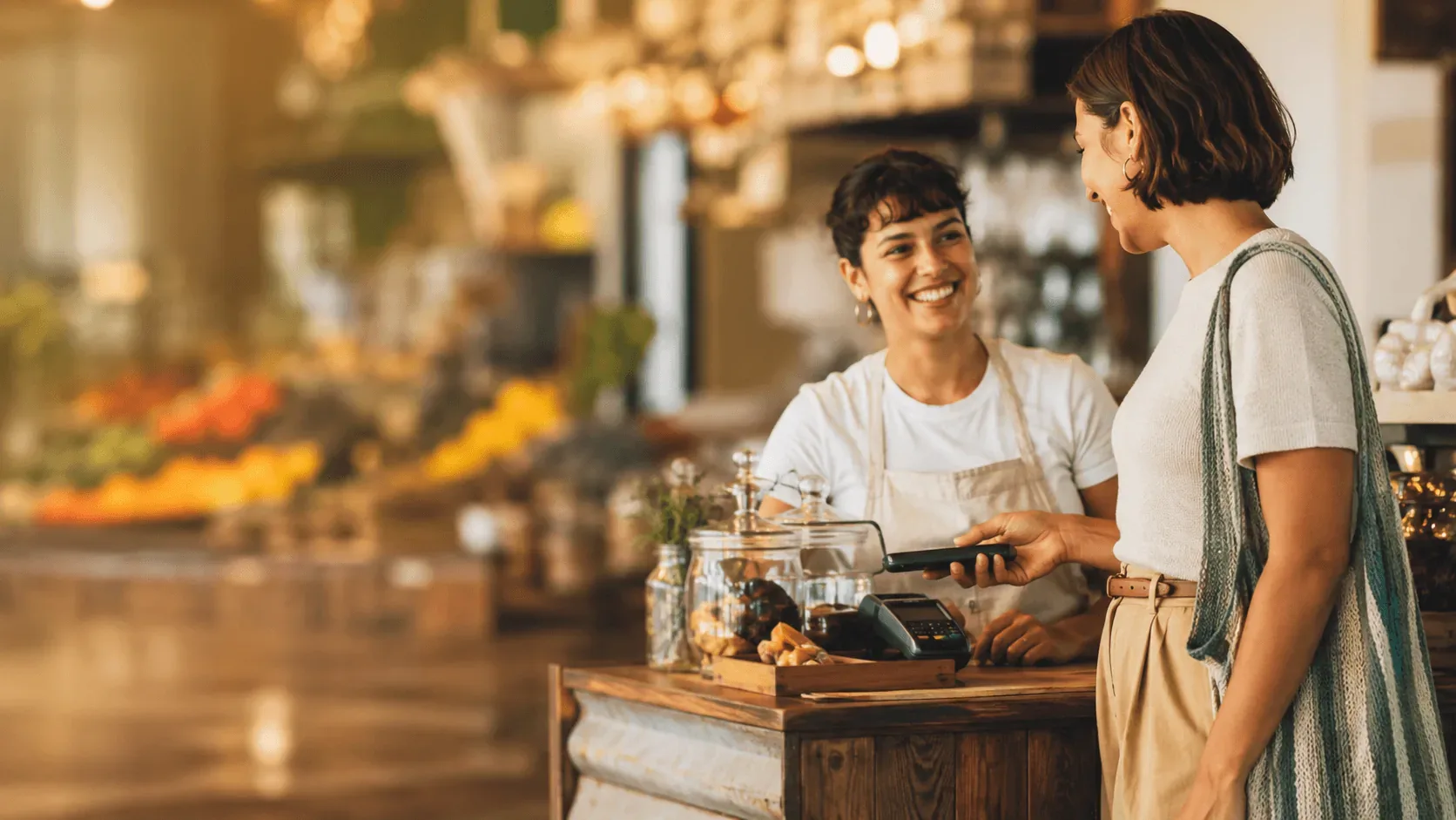 A customer paying by card at a warm, bustling local café counter