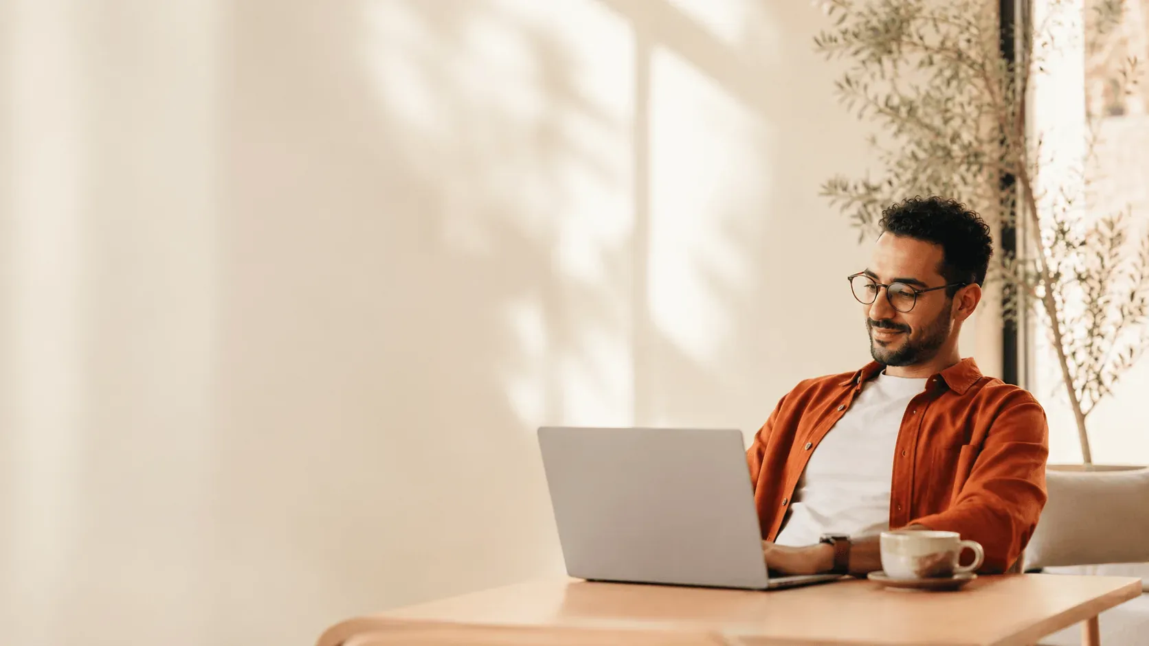 A freelancer working on a laptop in a sunlit café
